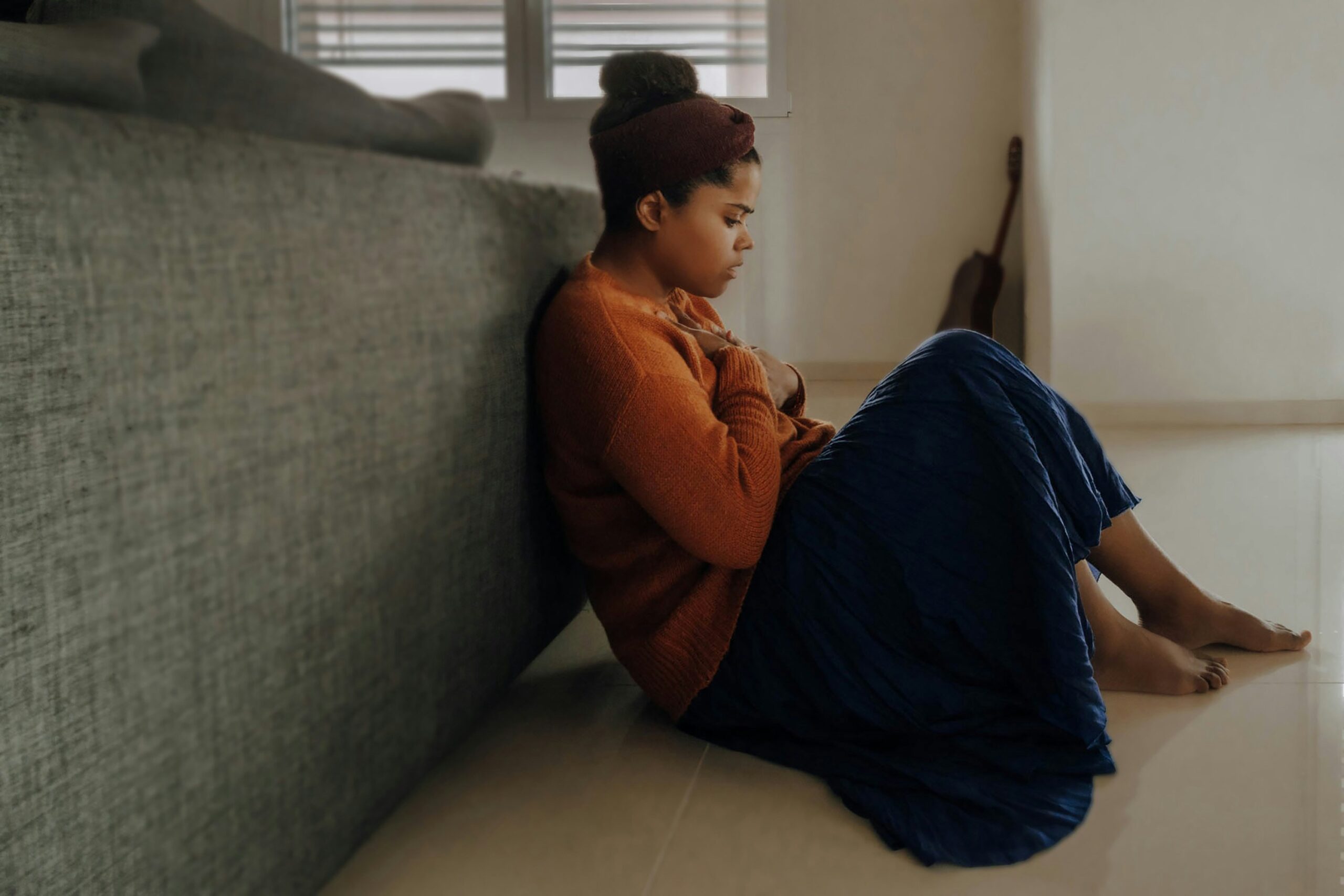 Woman sitting on the floor with arms wrapped around herself, exhausted and tense
